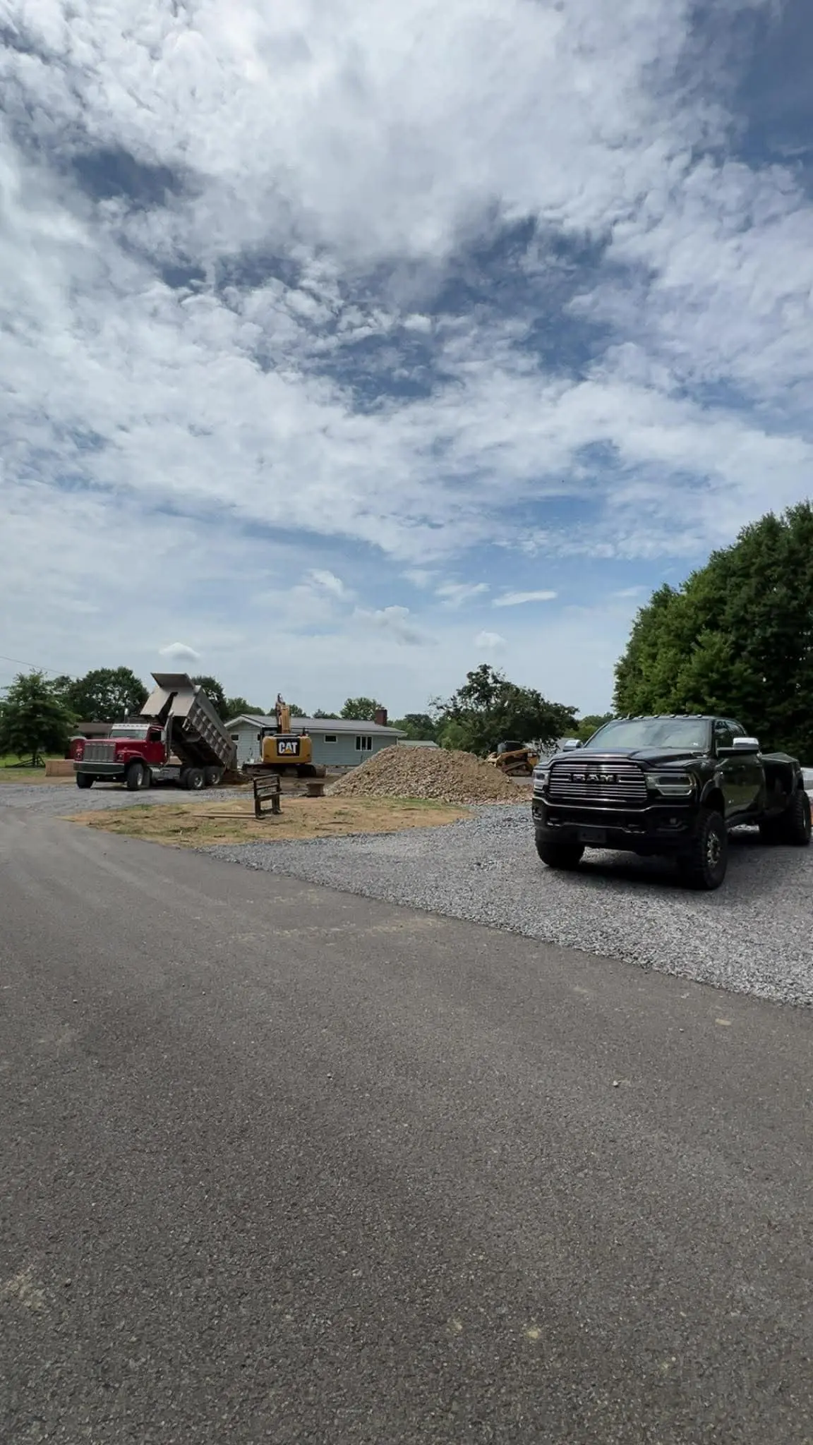 Dump truck and pickup with material stockpile by Poole Dirt Work